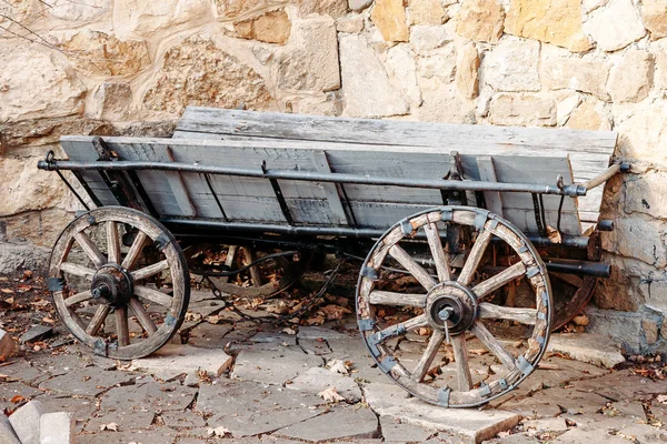 Vieux chariot en bois sur fond de mur de pierre étrange — Photo