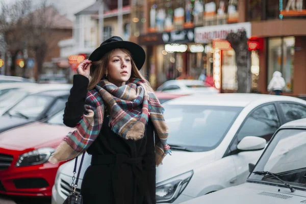 Giovane donna in cappotto nero, cappello e sciarpa. ragazza a piedi intorno ci — Foto Stock