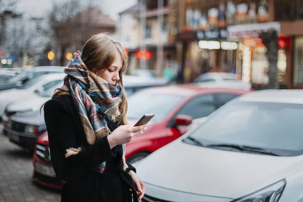 Женщина смотрит на мобильное устройство на осенней улице молодой кавказский — стоковое фото