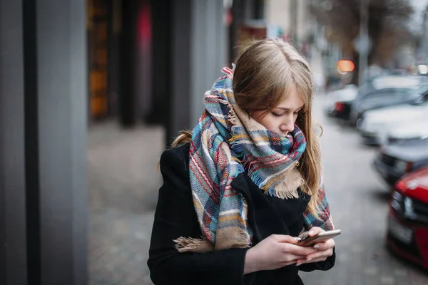 Женщина смотрит на мобильное устройство на осенней улице молодой кавказский — стоковое фото