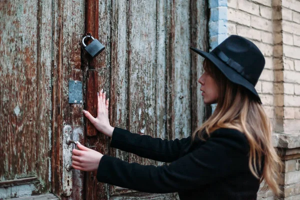 Blonde girl with long hair, in black coat in hat, trying to open — Stock Photo, Image