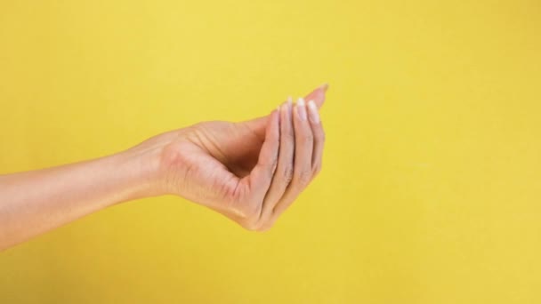 현금을 요구하는 손짓으로 손가락을 문질러 돈을 요구 한다. 노란 배경에 고립 된 여성의 손을 가까이 서 본 모습 — 비디오