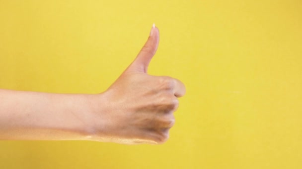 Női kéz mutatja hüvelykujj fel gesztus. Nő kéz emelkedik OK jó jel közelkép elszigetelt sárga képernyő háttér — Stock videók