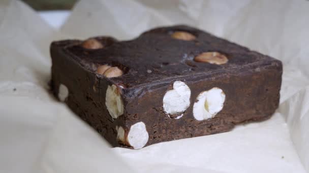 Dlaždice přírodní ručně vyrobená čokoláda s celými lískovými ořechy. Hra světla. — Stock video