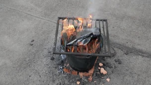 Molten hot tar in a bucket on the bricks. Roof repair. Fire from bucket. Grid on bucket — Stock Video