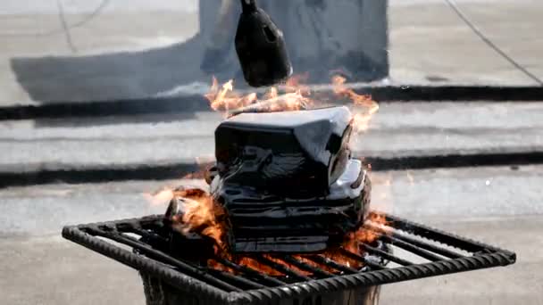 A worker melts tar with help of gas burner and fire. Pieces of bitumen are melted in bucket. Roof repair — Stock Video