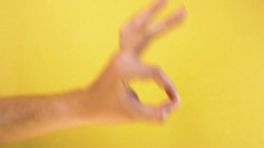 Erkek eli, sarı arka planda izole edilmiş iyi bir hareket gösteriyor.