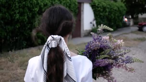 Mujer joven caminando con un ramo de flores en la calle de cerca. 4K — Vídeos de Stock