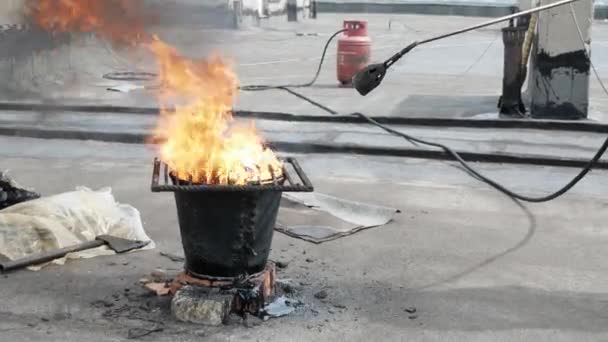 Réparation de toit. Un travailleur fait fondre le goudron à l'aide d'un brûleur à gaz et d'un feu pour réparer le toit — Video