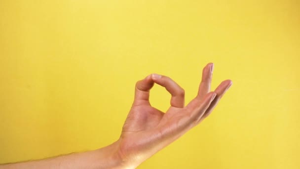Αρσενικό χέρι δείχνει OK χειρονομία απομονώνονται σε κίτρινο φόντο — Αρχείο Βίντεο