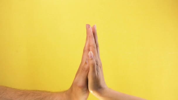 Mão masculina e feminina juntas. Mão masculina abraços mão feminina isolado no fundo amarelo — Vídeo de Stock