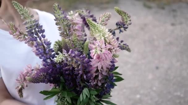 En vacker flicka förvandlar en blombukett i sina händer. Flickan tittar på blommorna. Vacker närbild — Stockvideo