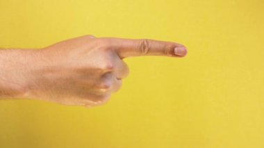 Erkek eli sarı arka planda izole edilmiş bir şeyi işaret ediyor. Yakın çekim