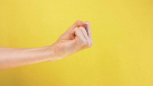 Vrouw vuist. gebaar bedreigen, agressie tegen geïsoleerde gele achtergrond — Stockvideo