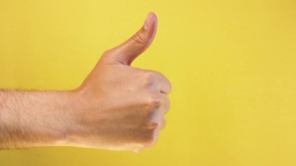 Cropped man hand showing thumb up gesture sign isolated yellow background — Stock Video