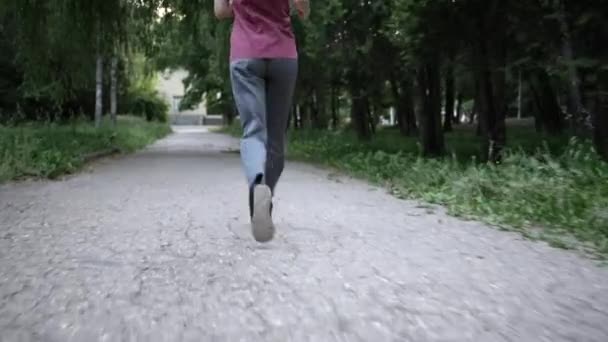Μια νεαρή αθλήτρια στο καλοκαιρινό πάρκο για τρέξιμο. η θέα από πίσω — Αρχείο Βίντεο
