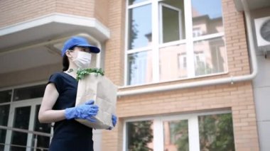 Kurye, koruyucu maskeli kurye ve tıbbi eldivenli teslimatçı paket yemek getiriyor. Karantina altında teslimat hizmeti, hastalık salgını, koronavirüs covid-19 salgını. Seçici odak
