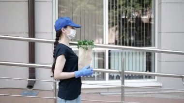 Kurye, koruyucu maskeli kurye ve tıbbi eldivenli teslimatçı paket yemek getiriyor. Karantina altında teslimat hizmeti, hastalık salgını, koronavirüs covid-19 salgını. Evde kal.