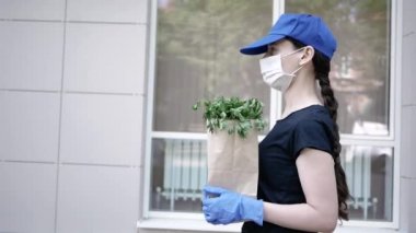 Kurye, koruyucu maskeli kurye ve tıbbi eldivenli teslimatçı paket yemek getiriyor. Karantina altında teslimat hizmeti, hastalık salgını, koronavirüs covid-19 salgını. Evde kal.