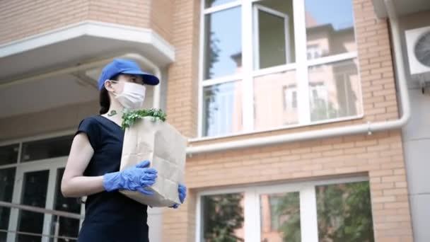 宅配便、保護マスクと医療用手袋の配達人はテイクアウト食品を提供します。隔離下での配送サービス,病気の発生,コロナウイルスcovid-19パンデミック条件.選択的焦点 — ストック動画