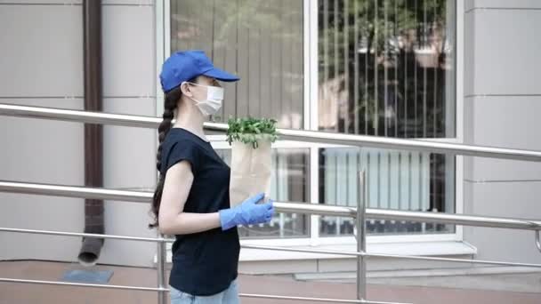 Koerier, bezorger met beschermend masker en medische handschoenen levert afhaalvoedsel. Bezorgingsdienst onder quarantaine, ziekte-uitbraak, coronavirus covid-19 pandemie. Blijf thuis. — Stockvideo