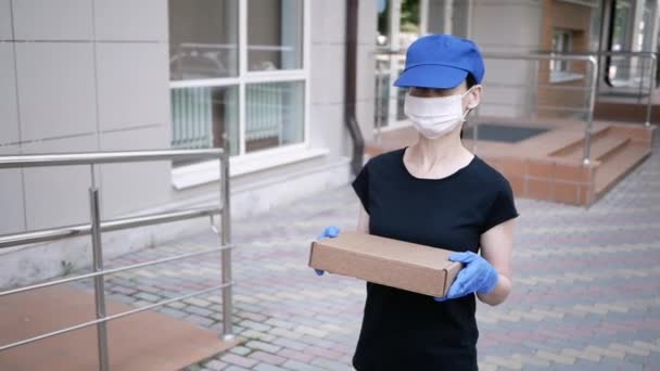 Carteiro, homem de entrega em máscara protetora e luvas médicas carregam pacote de caixa pequena. Serviço de entrega em quarentena, condições pandémicas. Conceito de distanciamento social — Vídeo de Stock