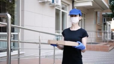 Kurye, koruyucu maskeli kurye ve tıbbi eldivenli teslimatçı paket pizza getiriyor. Karantina altında teslimat hizmeti, hastalık salgını, koronavirüs covid-19 salgını. Evde kal.