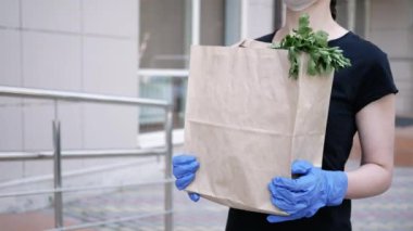 Kurye, koruyucu maskeli kurye ve tıbbi eldivenli teslimatçı paket yemek getiriyor. Karantina altında teslimat hizmeti, hastalık salgını, koronavirüs covid-19 salgını. Evde kal.