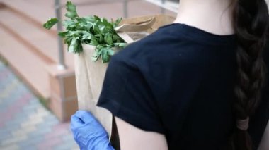 Kurye, koruyucu maskeli kurye ve tıbbi eldivenli teslimatçı paket yemek getiriyor. Karantina altında teslimat hizmeti, hastalık salgını, koronavirüs covid-19 salgını. Evde kal. Yakın plan.