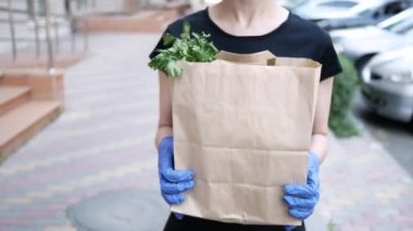 Kurye, koruyucu maskeli kurye ve tıbbi eldivenli teslimatçı paket yemek getiriyor. Karantina altında teslimat hizmeti, hastalık salgını, koronavirüs covid-19 salgını. Evde kal.