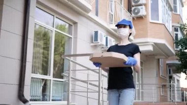 Kurye, koruyucu maskeli kurye ve tıbbi eldivenli teslimatçı paket pizza getiriyor. Karantina altında teslimat hizmeti, hastalık salgını, koronavirüs covid-19 salgını. Evde kal.