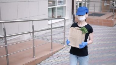 Kurye, koruyucu maskeli kurye ve tıbbi eldivenli teslimatçı paket yemek getiriyor. Karantina altında teslimat hizmeti, hastalık salgını, koronavirüs covid-19 salgını. Evde kal.