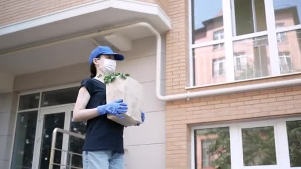 Koerier, bezorger met beschermend masker en medische handschoenen levert afhaalvoedsel. Bezorgingsdienst onder quarantaine, ziekte-uitbraak, coronavirus covid-19 pandemie. Blijf thuis. — Stockvideo