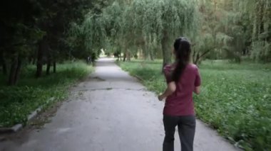 Yaz Parkı 'nda koşuya çıkan genç bir spor kadını. Arkadan manzara.