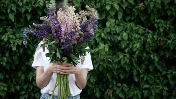 Närbild av oigenkännlig kvinna som håller en bukett blommor framför honom på bakgrunden av grön vägg från lities. 4K — Stockvideo
