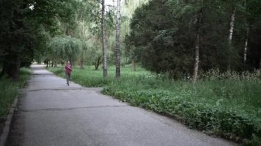 Genç esmer kadın yazın parkta koşuyor.