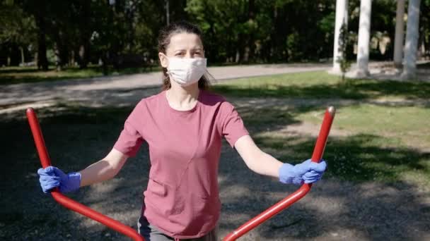 Junge Frau am Simulator im Park beobachtet Schutz vor Coronavirus covid-2019 ncov-19 Handschuhe und Mundschutz — Stockvideo