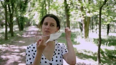 Yaz Parkı 'nda genç bir kadının portresi. Yüzündeki koruyucu maskeyi çıkarıyor ve derin bir nefes alıyor. Temiz havanın tadını çıkarıyor.