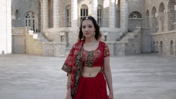 Hermoso sari indio étnico. Mujer joven en traje rojo, colorido, sensual, de boda y muy femenino: el sari indio camina por las viejas calles de la India. Ropa nacional tradicional de mujeres indias — Vídeos de Stock