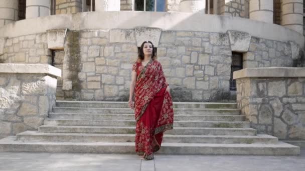 Bella Saree indiana etnica. Giovane donna in abito rosso, colorato, sensuale, da sposa e molto femminile - il sari indiano passeggia per le vecchie strade dell'India. Abbigliamento nazionale tradizionale delle donne indiane — Video Stock