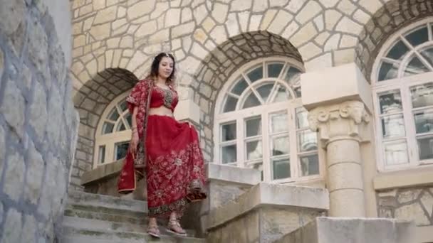 Gyönyörű indián szári. Fiatal nő piros, színes, érzéki, esküvő és nagyon nőies ruhát - indiai szári sétál a régi utcákon Indiában. Indiai nők hagyományos nemzeti ruházata — Stock videók