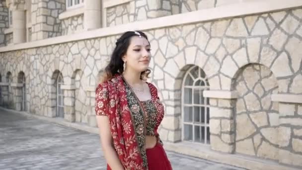 Gyönyörű indián szári. Fiatal nő piros, színes, érzéki, esküvő és nagyon nőies ruhát - indiai szári sétál a régi utcákon Indiában. Indiai nők hagyományos nemzeti ruházata — Stock videók