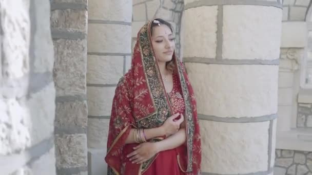 Hermoso sari indio étnico. Mujer joven en traje rojo, colorido, sensual, de boda y muy femenino: el sari indio camina por las viejas calles de la India. Ropa nacional tradicional de mujeres indias — Vídeo de stock
