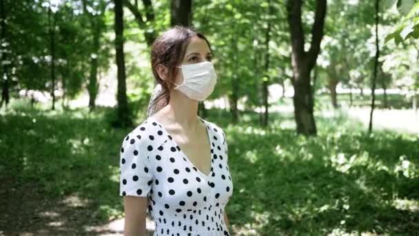 Retrato de mujer joven en paseos máscara médica protectora en el parque de verano — Vídeo de stock