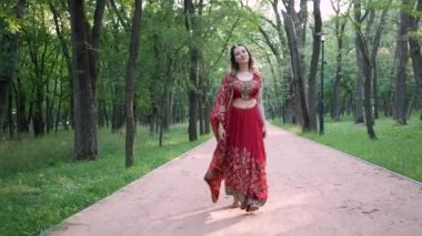 Hindistan 'da kırmızı sarili genç ve güzel bir kadın parkta yürüyordu.