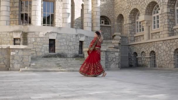 Donna indiana danza sulle strade dell'antica città di architettura dell'India vestita in rosso Sari, decorata con ornamenti tradizionali e disegni di hennè Mehendi su mani — Video Stock