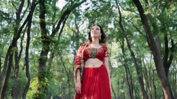 Портрет молодой женщины в индийском сари, гуляющей в парке — стоковое видео