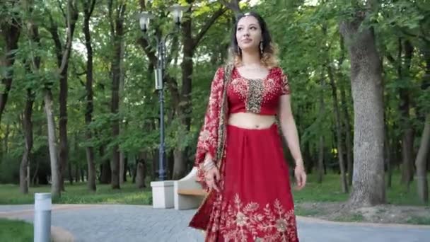 Giovane bella donna in indiano etnico rosso saree a piedi nel parco — Video Stock