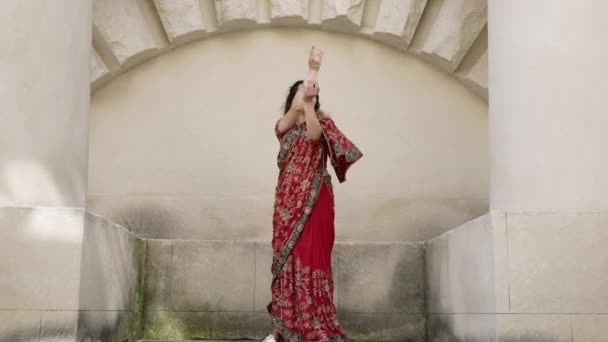 Donna indiana danza sulle strade dell'antica città di architettura dell'India vestita in rosso Sari, decorata con ornamenti tradizionali e disegni di hennè Mehendi su mani — Video Stock