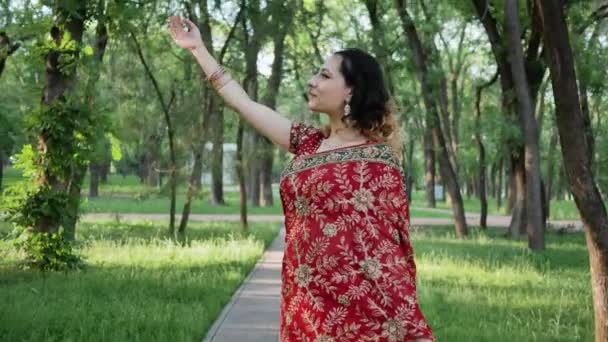 Jeune femme en saree indienne rouge posant dans le parc d'été — Video